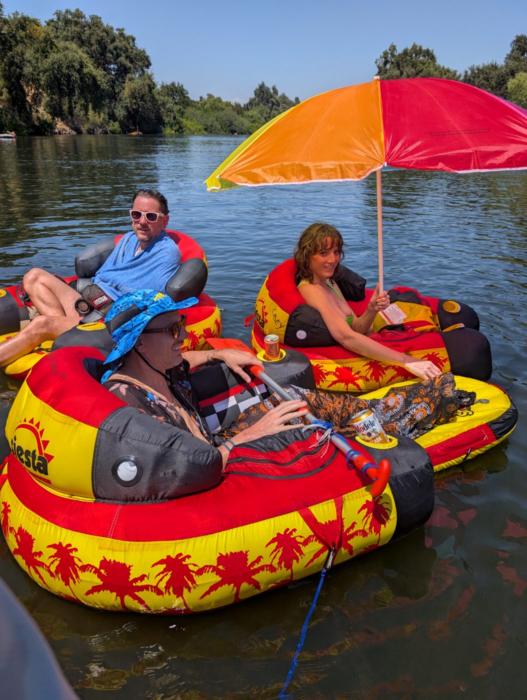 Three friends raft together under a bright beach umbrella