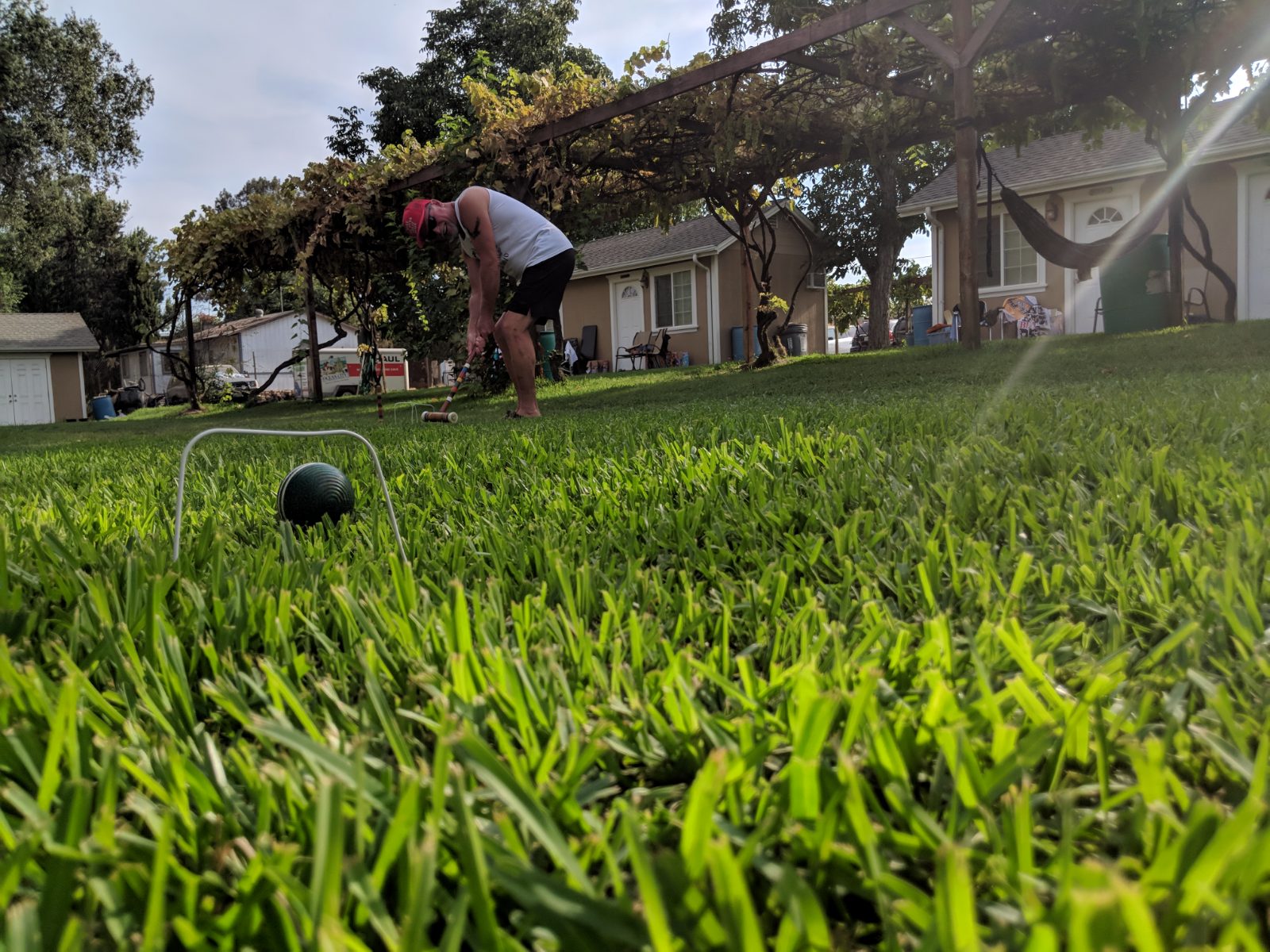 A camper lines up a croquet shot on the lawn at golden hour