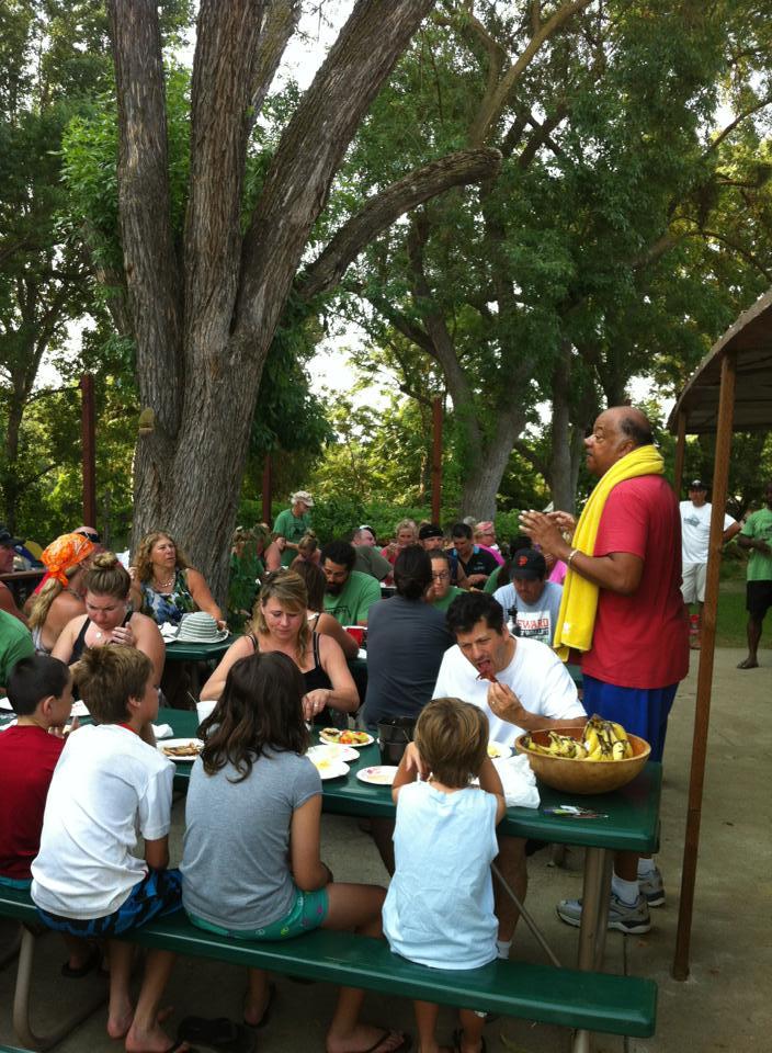 Campers gathered at long picnic tables for a communal dinner under the big trees