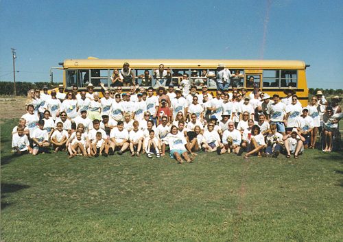 An early group photo lined up in front of the yellow school bus