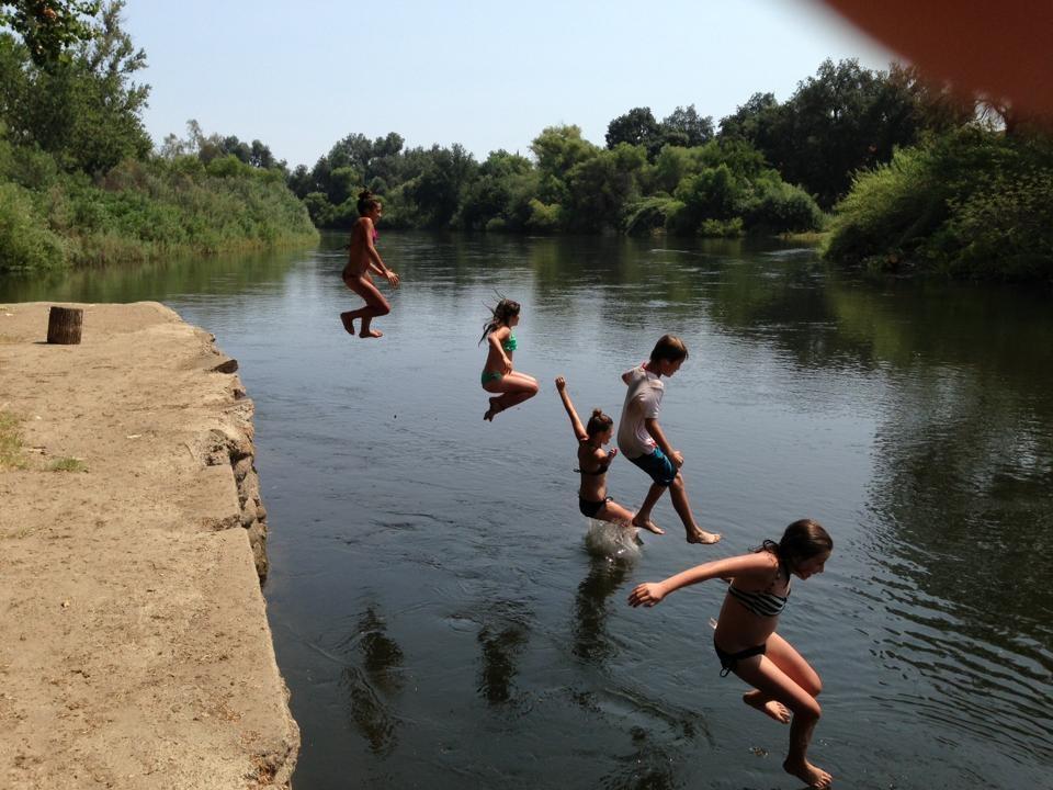 A line of kids leaping off the bank into the river
