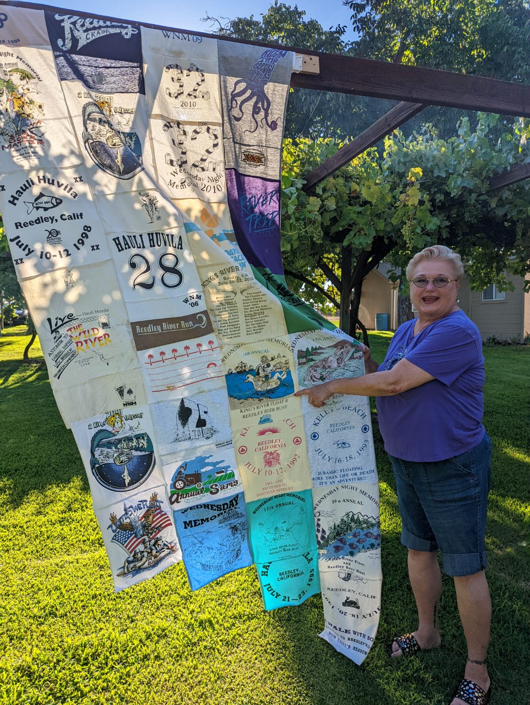 Decades of River Trip t-shirts sewn together into a quilt, held up in the sun