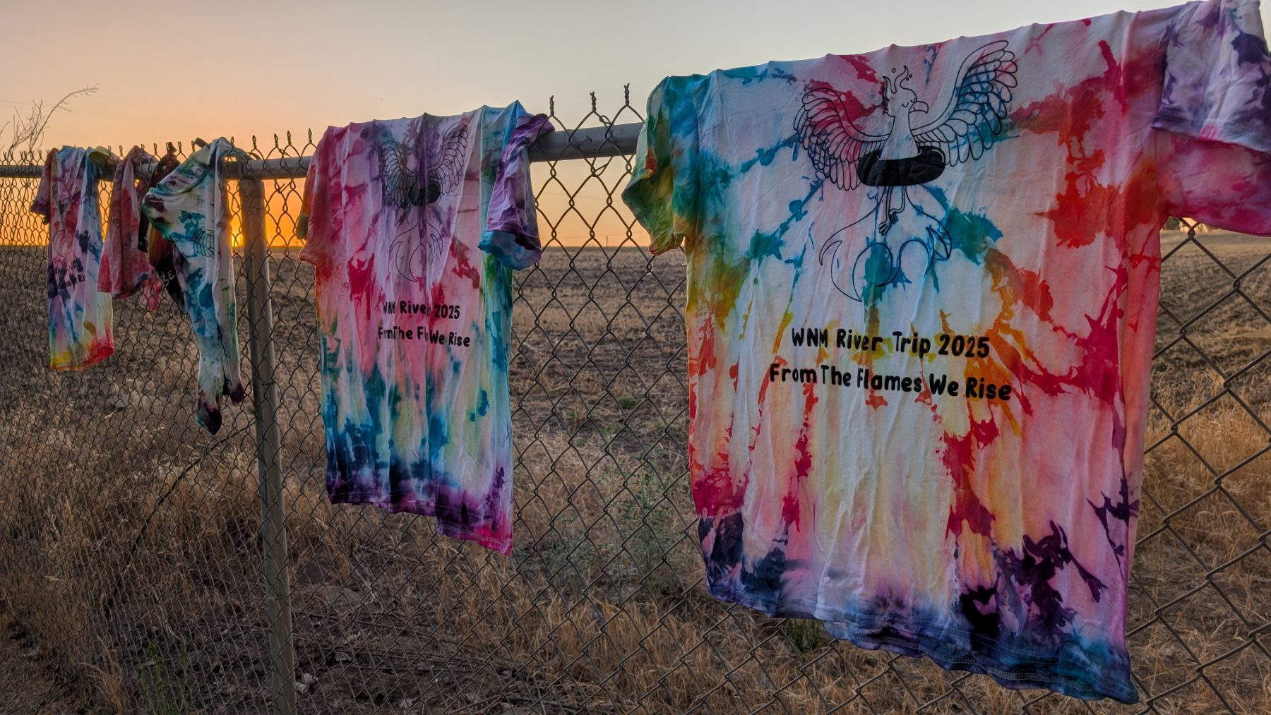 This year's tie-dye trip shirts drying on the fence against a valley sunset
